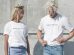 man and woman in white-and-gray force majeure-printed crew-neck t-shirts standing near gray concrete wall