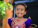 selective focus photography of girl smiling while standing near plant at daytime