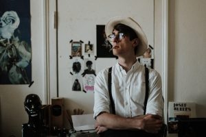 man wearing black suspenders standing behind door