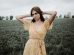 woman in yellow floral dress standing on green grass field during daytime