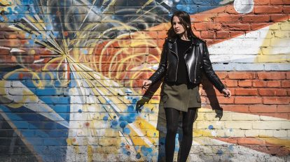 woman wearing black leather jacket standing near wall