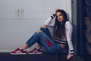 woman in white long sleeve shirt and blue denim jeans sitting on white wooden fence